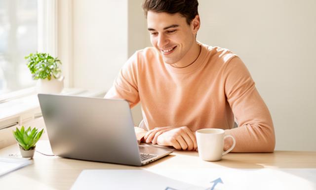 Tevreden jonge professional werkt aan een laptop in een lichte werkruimte in Nieuw-Vennep met een subtiele grafiek op het bureau